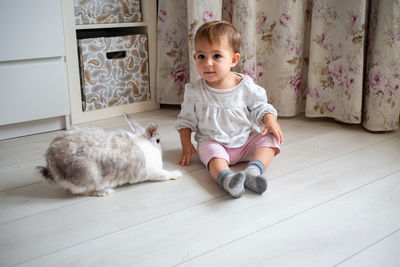 Cute baby girl sitting on floor at home