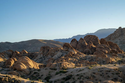 Scenic view of rocky desert and distant mountains against clear sky