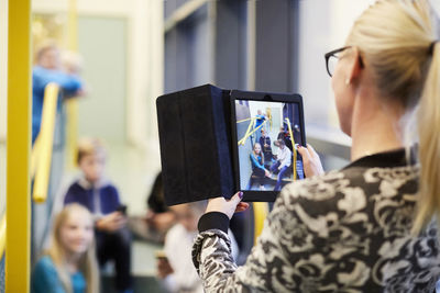 Teacher photographing students through digital tablet in school