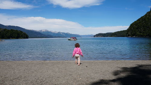 Rear view of woman on shore against sky