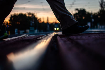 Low section of man crossing railroad tracks during sunset