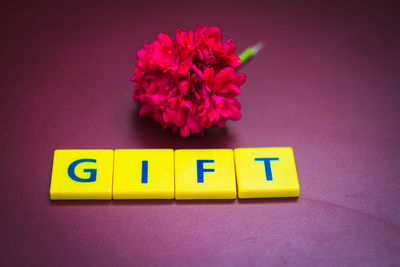 High angle view of toy blocks with gift text by flowers on table