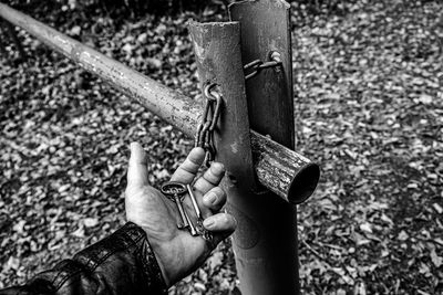 Cropped image of man holding keys by metal pole