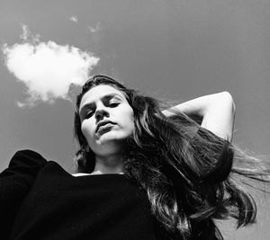 Young woman looking away against sky