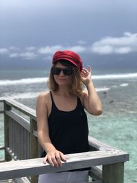 Young woman wearing sunglasses on beach against sky