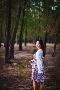 Full length of woman standing on field in forest