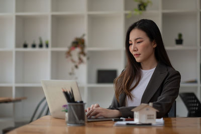 Young woman using phone while sitting on table