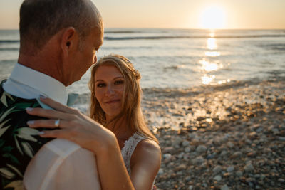 Midsection of couple at beach against sky