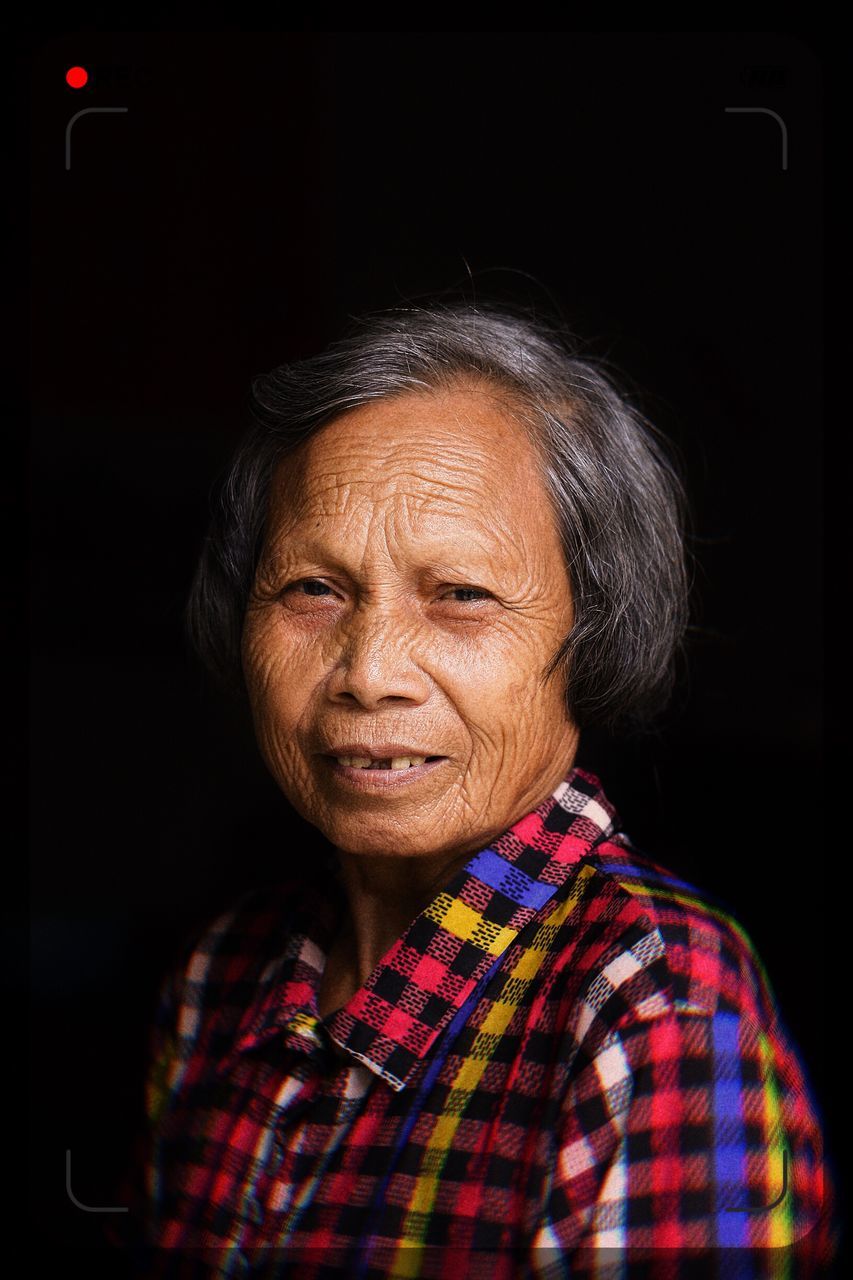 one person, portrait, headshot, adult, senior adult, indoors, real people, front view, lifestyles, black background, smiling, males, men, wrinkled, studio shot, looking at camera, casual clothing, looking, contemplation, hairstyle