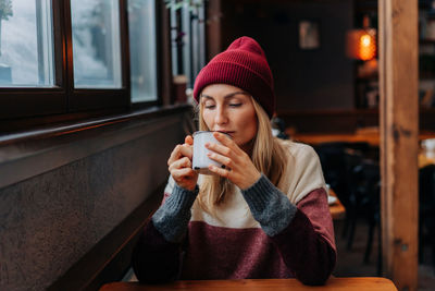 Apres ski, a woman in a coffee sitting in a cozy bar drinks coffee.