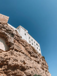 Low angle view of rock formation against clear blue sky