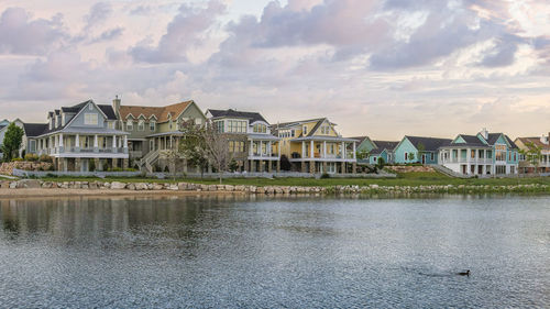 Houses by lake against sky