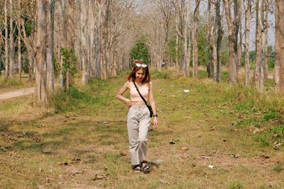 Full length portrait of smiling young woman in forest