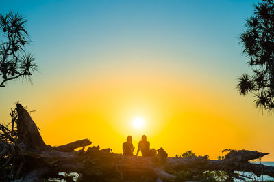 Silhouette people against orange sky