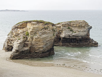 Rock formation on beach against sky