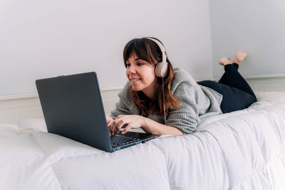 Young woman using laptop on bed at home