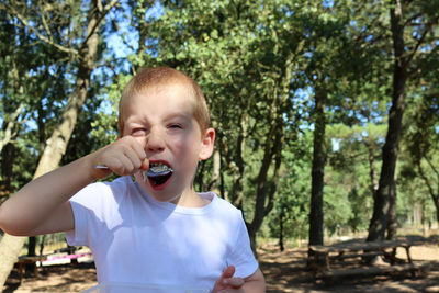 Portrait of young man standing against trees