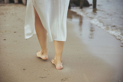 The girl walks alone on the seashore. 