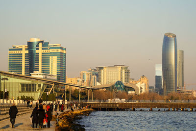 Modern buildings by river against sky in city