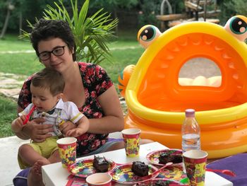 Mother with son having cakes by inflatable raft at yard