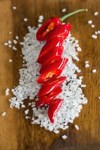 High angle view of red chili pepper with salt on wooden table