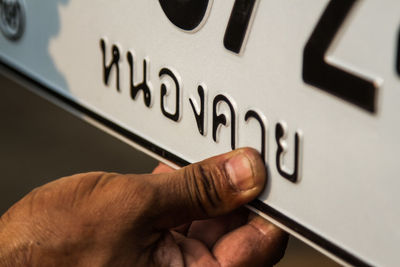 Close-up of human hand holding license plate