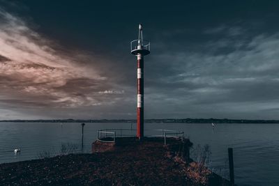 Lighthouse by sea against sky