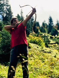 Young man aiming arrow in forest