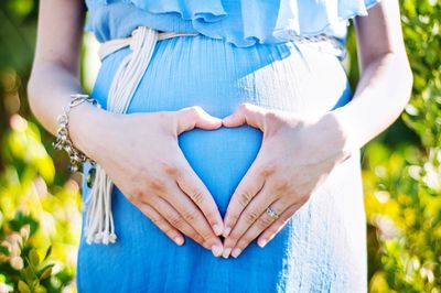 Pregnant woman forming heart with hands on belly