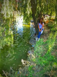 Full length of woman sitting by lake