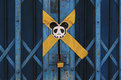 Close-up of yellow sign on metal fence