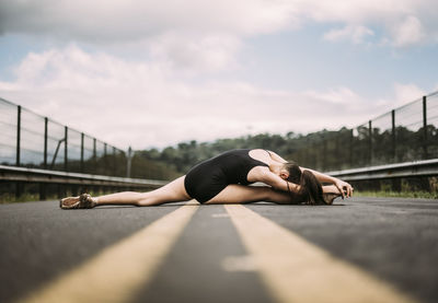Surface level of young woman stretching on road
