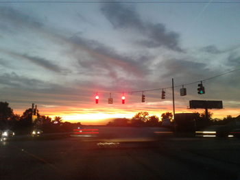 Cars on road against sky at sunset