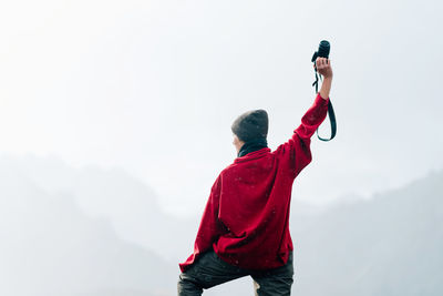 Rear view of man standing on mountain against sky