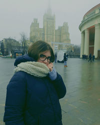 Portrait of young woman standing in city during winter