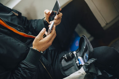 Man checking blood sugar level with glaucometer while using mobile phone in train