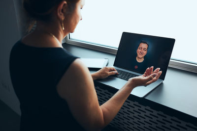 Midsection of woman using laptop at table