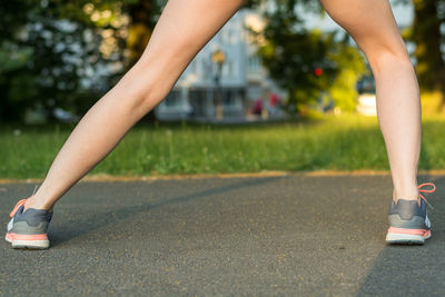 Low section of woman stretching on road