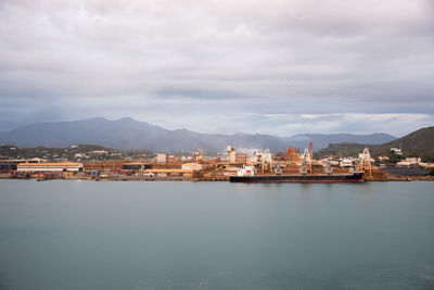 City at waterfront against cloudy sky