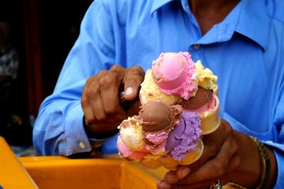 Midsection of man scooping ice cream in cones