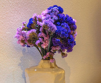 Close-up of purple flower vase on table against wall