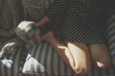 Low section of woman with puppy on sofa at home