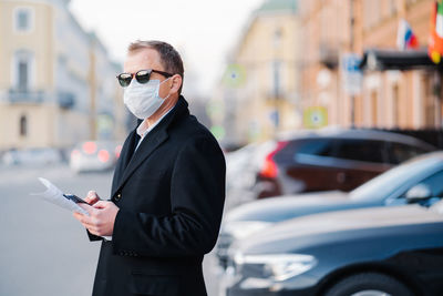 Side view of businessman wearing mask standing on street