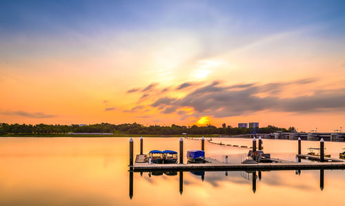 Scenic view of boats in calm lake at sunset