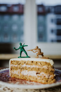 Two toy soldiers fighting on the top of a piece of cake about having a desert or not