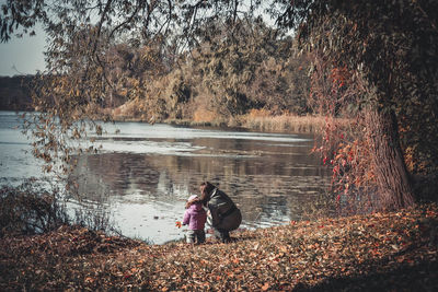 Woman at lakeshore in forest during autumn