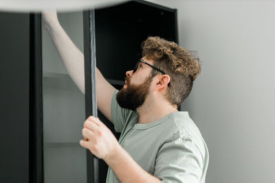 Side view of man looking through window