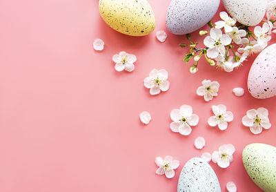 Colorful easter eggs with spring blossom flowers over pink background. colored egg holiday border.