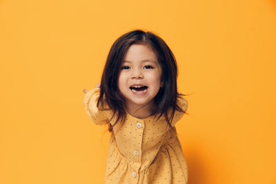 Portrait of young woman against yellow background