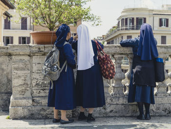 Rear view of nuns standing by retaining wall